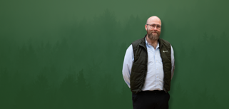 David Mariasdotter, Sustainability consultant at Monitor ERP, standing with hands behind back in front of green background