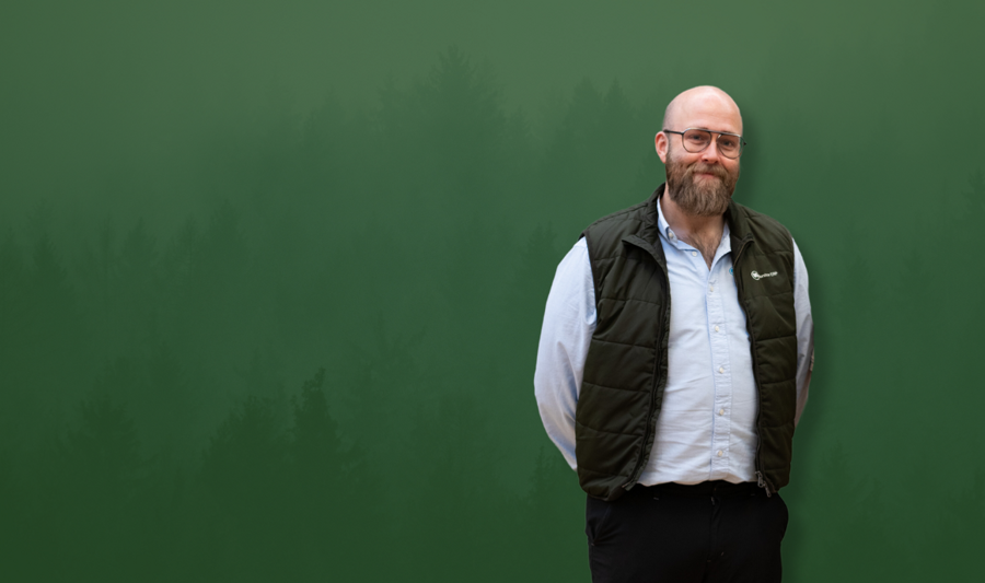 David Mariasdotter, Sustainability consultant at Monitor ERP, standing with hands behind back in front of green background