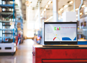 Monitor ERP dashboard displayed on a laptop in a factory environment.