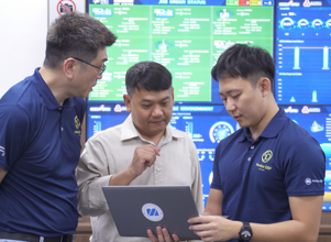 Three men looking at a computer with Monitor