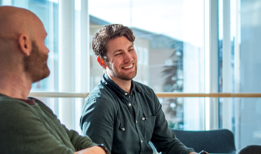 A couple of men sitting at a table with laptops.