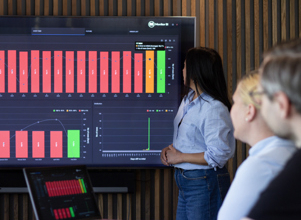 Three people in a conference room looking at a graph.