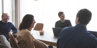A group of people sitting around a table with laptops.