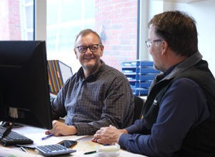 Two men sitting behind a computer