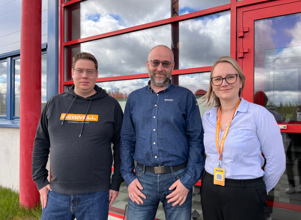 Three people outside a factory