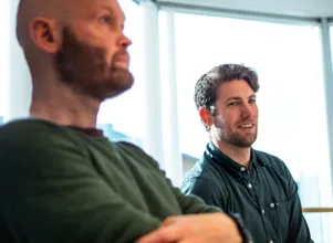 Two men sitting next to each other in front of a window.