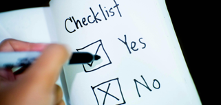 A hand is writing checklist on a book.