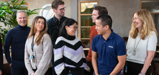 En grupp medarbetare på Monitor står och skrattar och pratar med varandra.