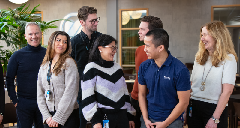 En grupp medarbetare på Monitor står och skrattar och pratar med varandra.