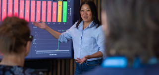 A woman at Monitor ERP giving a presentation to a group of people about Monitor BI (business intelligence)