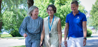 Tre medarbetare går en promenad utomhus. De skrattar.