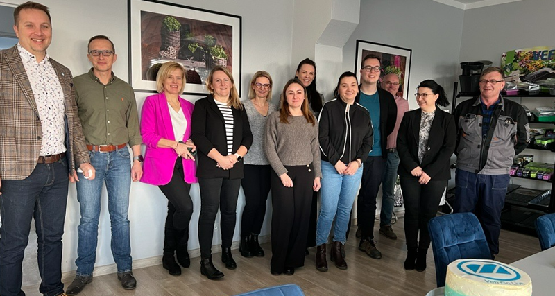 Monitor and Vefi employees standing in front of the cake.