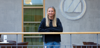 Troja Stenström Schönborg står och lutar sig mot ett räcke inne på Monitors huvudkontor i Hudiksvall.