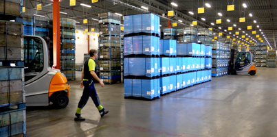 A man walking through a warehouse filled with boxes.