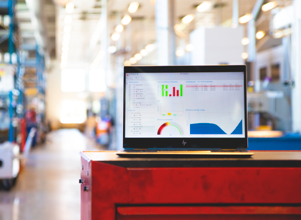 Monitor ERP dashboard displayed on a laptop in a factory environment.