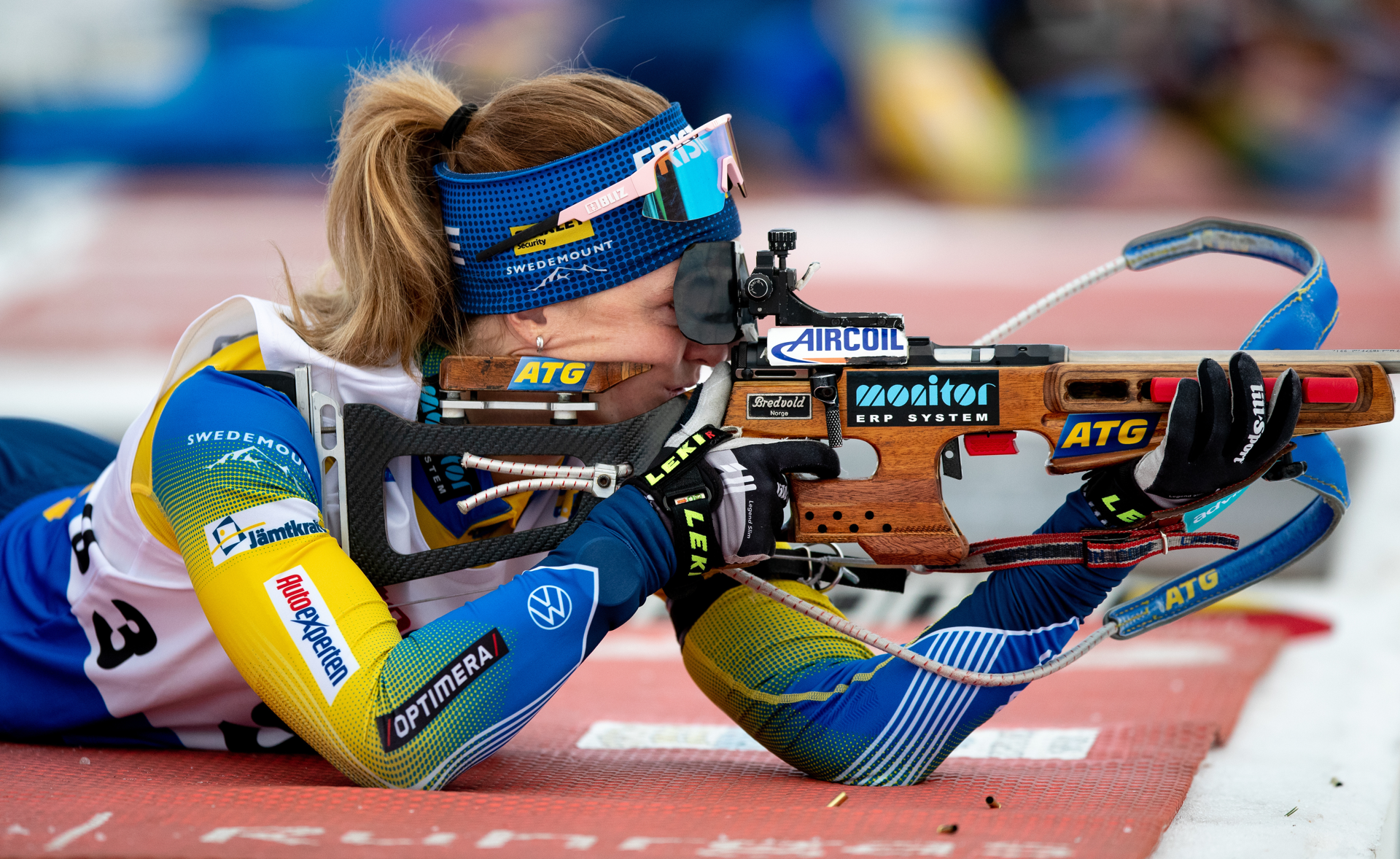 Åkare i skidskyttelandslaget skjuter mot tavla i liggande position. 
