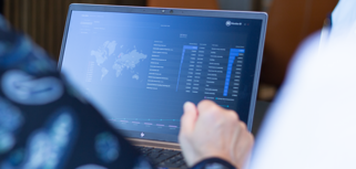 A person sitting in front of a laptop computer with Monitor BI (business intelligence) dashboards. 