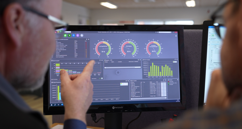 A person pointing at a screen showing Monitor ERP dashboard.