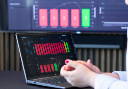 A person sitting in front of a laptop computer with Monitor BI (business intelligence) dashboards. 