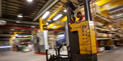 A forklift in a warehouse moving around.