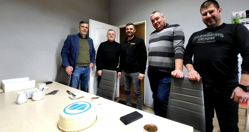 Monitor and Tech-Exim employees standing in front of the cake.