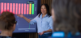 A woman at Monitor ERP giving a presentation to a group of people about Monitor BI (business intelligence)