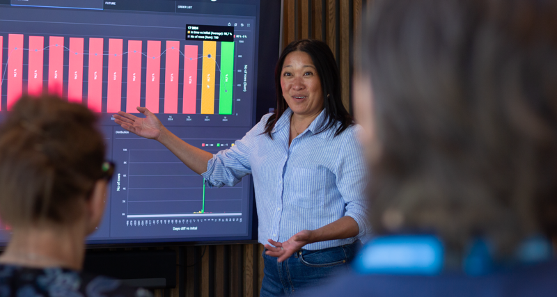 A woman at Monitor ERP giving a presentation to a group of people about Monitor BI (business intelligence)