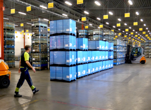 A man walking through a warehouse filled with boxes.