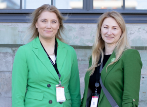 Two women standing next to each other dressed in green