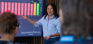 A woman at Monitor ERP giving a presentation to a group of people about Monitor BI (business intelligence)