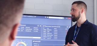 A man standing in front of a large screen displaying the ERP system Monitor ERP. 