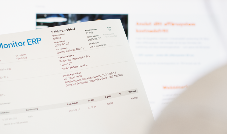 A woman holding an invoice from Monitor ERP in front of a computer screen.