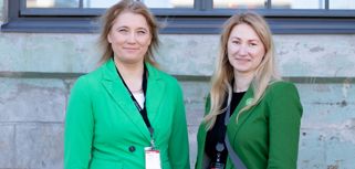 Two women standing next to each other dressed in green