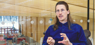 En man sitter i en stol framför en glasvägg.