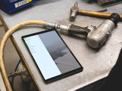 En surfplatta ligger på ett metallbord och visar menyn i Monitor Mobile.