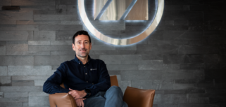 Adrian Aptowitzer, VD för Monitor ERP Sverige, sitter i en fåtölj framför en skylt med Monitor-loggan. 