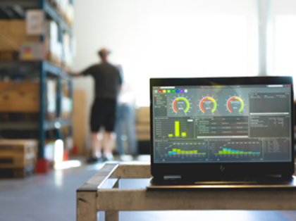 Monitor ERP dashboard som visas på en laptop ståendes på ett bord i en fabriksmiljö.