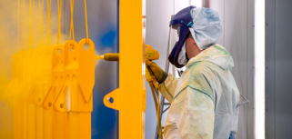 A man in a protective suit spray painting a wall.