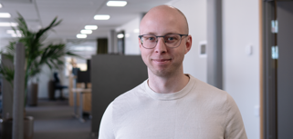 Jonas Lundin står i ett kontorslandskap och tittar in i kameran. 