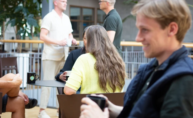 Person sitter och fikar med kollegor.