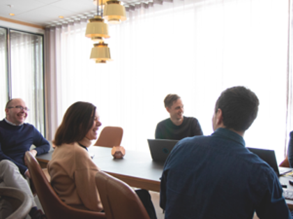 A group of people sitting around a table with laptops.