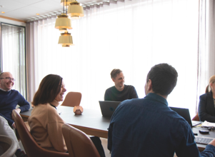 A group of people sitting around a table with laptops.