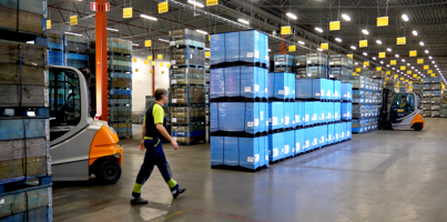 A man walking through a warehouse filled with boxes.