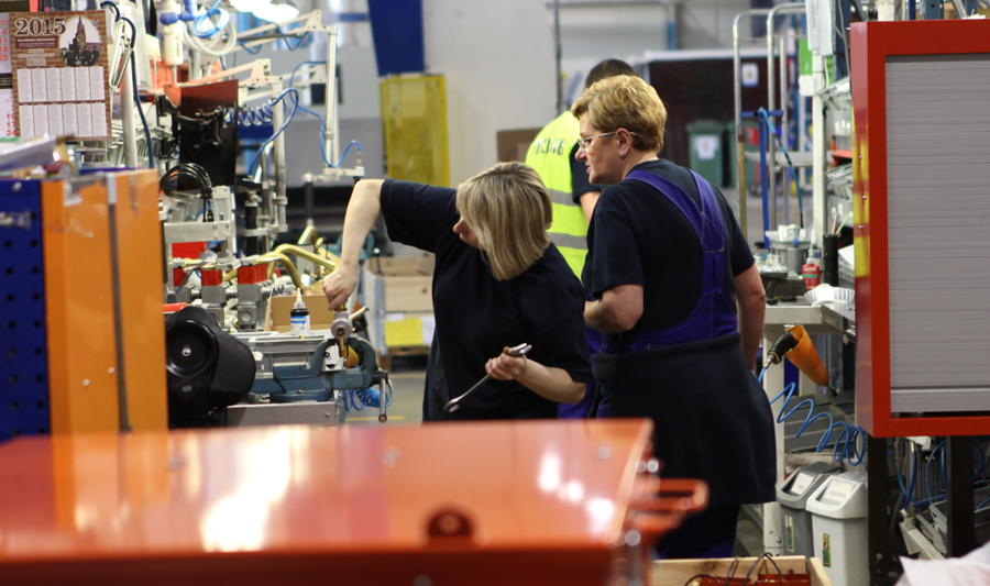 Två personer som arbetar med en maskin i en fabrik. 
