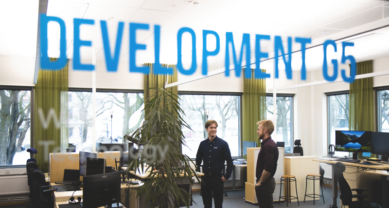 Viktor Rosvall står i ett kontorslandskap och pratar med kollegor.