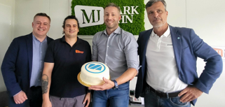 A group of men standing next to each other holding a cake.