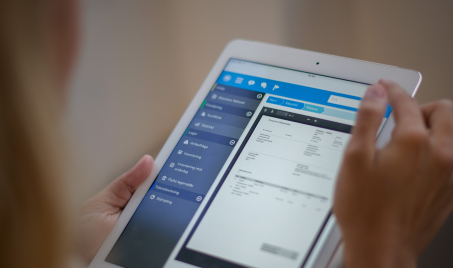 A woman is holding a tablet displaying a digital invoice. 