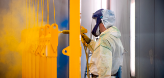 En man i skyddsdräkt som spraymålar en vägg.