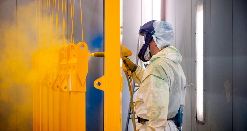 En man i skyddsdräkt som spraymålar en vägg.