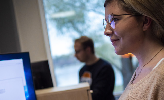 A woman wearing glasses looking at a computer screen.